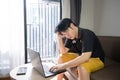 Stressed asian businessman sitting on a sofa at home and working on a laptop. Royalty Free Stock Photo