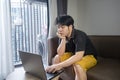 Stressed asian businessman sitting on a sofa at home and working on a laptop. Royalty Free Stock Photo