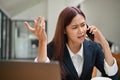 Stressed asian businesswoman arguing on the phone with her colleague. Serious, Unsatisfied Royalty Free Stock Photo