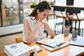 Stressed Asian businesswoman examining financial report paperwork at her desk Royalty Free Stock Photo