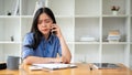 A stressed Asian businesswoman is having a serious conversation over the phone