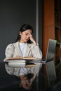 Stressed Asian businesswoman at her desk, suffering from a headache or eye strain Royalty Free Stock Photo