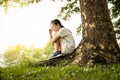 Stressed asian child girl was sitting alone crying under the tree at park,desperate female teenage with depressive symptoms feel