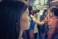 Stressed Asian girl using a smartphone in mass rapid transit among people