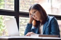 Stressed Asian glasses woman in blue shirt thinking.