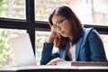 Stressed Asian glasses woman in blue shirt thinking.