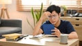 Stressed asian male frustrated with financial problems, managing household expenses at home