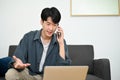 Stressed Asian male looking at laptop screen while having a serious conversation over the phone Royalty Free Stock Photo