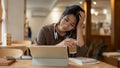 A stressed Asian woman is concerned about her project\'s deadline while working remotely at a cafe Royalty Free Stock Photo