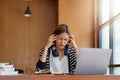 Stressed Asian woman cover her face with hand and feel upset from work in front of laptop computer on desk at office Royalty Free Stock Photo