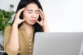 Stressed Asian woman having headache, migraine at work tired from working on computer hand touching her head Royalty Free Stock Photo