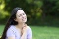 Stressed asian woman scratching neck in a park