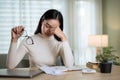 A stressed Asian woman is worried about financial problems while sitting at a table Royalty Free Stock Photo