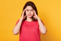 Stressed beautiful woman wears casual t shirt, touching temples and has terrible headache, attractive young lady looks tired. Royalty Free Stock Photo