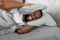 Stressed black man covering ears lying in bed Royalty Free Stock Photo