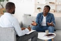Stressed black man explaining his problems to psychologist at individual therapy session