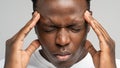 Exhausted upset African American man feeling pain suffering from migraine massaging temples. Studio. Royalty Free Stock Photo