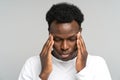 Exhausted upset African American man feeling pain suffering from migraine massaging temples. Studio. Royalty Free Stock Photo