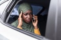 Stressed black muslim lady riding car on backseat and talking on cellphone Royalty Free Stock Photo