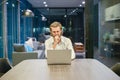 Stressed blonde business man using a laptop in living room at ni