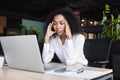 Stressed business woman sitting at office workplace looking at laptop computer. Tired and overworked businesswoman has headache Royalty Free Stock Photo