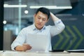 Stressed businessman holding face with his hands because having trouble. Bankrupt Asian Male is sitting with laptop Royalty Free Stock Photo