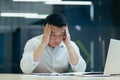 Stressed businessman holding face with his hands because having trouble. Bankrupt Asian Male is sitting with laptop Royalty Free Stock Photo