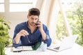 Stressed businessman making a call while sitting at office desk Royalty Free Stock Photo