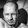 A man gives himself a cold shower after work to calm down after hard frustrated and nervous day at his job close up black and whit
