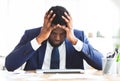 Stressed businessman sitting in office with hand on forehead Royalty Free Stock Photo