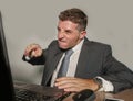 Stressed businessman in suit and tie working angry at office laptop computer desk looking furious and upset in financial business Royalty Free Stock Photo