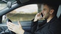 Stressed businessman swearing and talking phone while sitting inside car outdoors Royalty Free Stock Photo