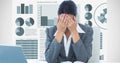 Stressed businesswoman sitting at desk against graphs