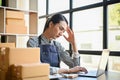 Stressed and concentrated Asian female online shop owner using laptop, checking online orders