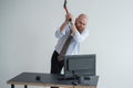 Stressed crazy businessman smashing his computer in office using ax problem concept. The man has problems at work and Royalty Free Stock Photo