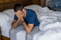 Stressed, depressed or grieving man sitting on bed covering face with hands and crying. Worried and frustrated male