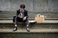 Stressed Asian businessman sits on a staircase with a box of his personal stuff after getting fired Royalty Free Stock Photo