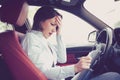 Stressed desperate young woman driver with documents sitting inside her car