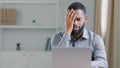 Stressed disappointed African American ethnic bearded man holding head with headache tired overworked manager reading Royalty Free Stock Photo