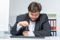 Stressed employee sits at the desk and holds his glasses in his hand