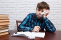 Stressed and exhausted pupil with torn papers sitting at the des Royalty Free Stock Photo