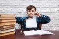 Stressed and exhausted schoolboy tearing papers sitting at the d Royalty Free Stock Photo