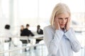 Stressed fatigued mature businesswoman suffer from headache in o