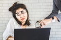 Stressed female Asian worker sitting at desk feeling pressure from annoying boss