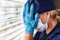 Stressed Female Doctor or Nurse On Break At Window Wearing Medical Face Mask and Crying