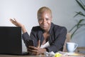 Stressed and frustrated afro American black woman working upset at office laptop computer desk gesturing angry looking at mobile p