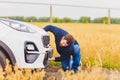 Stressed and frustrated driver pulling his hair while standing on the road next to broken car. Road trip problems and