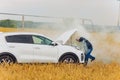 Stressed and frustrated driver pulling his hair while standing on the road next to broken car. Road trip problems and