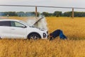 Stressed and frustrated driver pulling his hair while standing on the road next to broken car. Road trip problems and