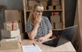 Stressed and frustrated elderly business woman holding hand on head while working on laptop in the home office, online Royalty Free Stock Photo